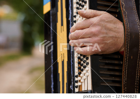 Man Playing Black Accordion Outdoors, Close-up Hand on Buttons, Musical Instrument, Summer Scene, Texture, Folk Music, Entertainment, Natural Light. 127440828