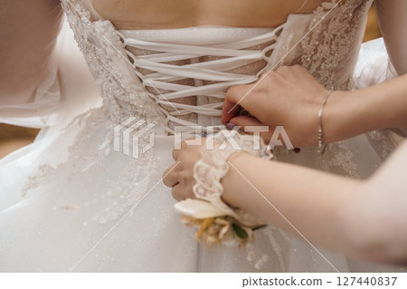 Wedding Dress Lacing Up: Pearl Corset Back Detail, Bridal Preparation, Ivory Gown, Lace Sleeves, Elegant Ceremony, Close-Up, Soft Lighting Wedding Dress Lacing Up: Pearl Corset Back Detail, Bridal Preparation, Ivory Gown, Lace Sleeves, Elegant Ceremony, Close-Up, Soft Lighting 127440837