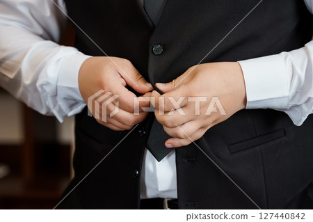 Groom Adjusting Vest Before Wedding Ceremony, Black Suit, White Shirt, Formal Attire, Elegant, Getting Ready, Handsome Man, Close-up Shot. 127440842