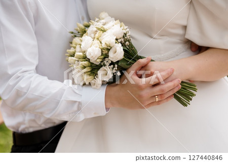 Romantic Wedding Moment with White Bridal Bouquet, Close-Up of Hands with Rings, Stylish Couple, Ivory Dress, Classic Elegance, Formal Attire 127440846