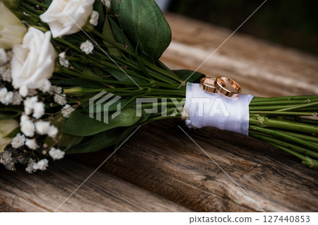 Wedding Rings on Bouquet: Golden Bands and White Flowers Rustic Marriage Symbolism, Love, Commitment, Close-up Shot, Natural Light Wedding Rings on Bouquet: Golden Bands and White Flowers Rustic Marriage Symbolism, Love, Commitment, Close-up Shot, Natural Light 127440853