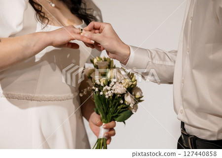 Romantic Wedding Ceremony Exchange of Rings Focus on Hands Bouquet White Flowers Traditional Celebration Love Commitment Partnership Vows. 127440858