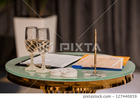 Elegant Wedding Table Setting with Champagne Flutes, Gold Accents, and Contract, Luxurious Celebration, Romantic Mood, Green and Gold Color Palette 127440859