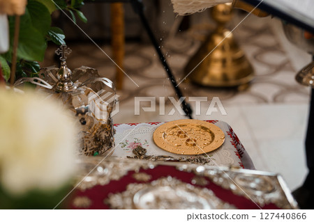 Eastern Orthodox Wedding Ceremony: Blessing of the Rings with Silverware and Floral Arrangement, Gold Disks, Red Textile Background Eastern Orthodox Wedding Ceremony: Blessing of the Rings with Silverware and Floral Arrangement, Gold Disks, Red Textile Background 127440866