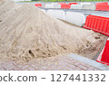 Red and white plastic barriers blocking the road. Pile of sand. Road repairs in the city 127441332