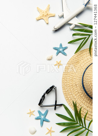 Summer vacation concept featuring airplane, sunglasses, straw hat, seashells, starfishes Summer vacation concept featuring airplane, sunglasses, straw hat, seashells, starfishes 127441368