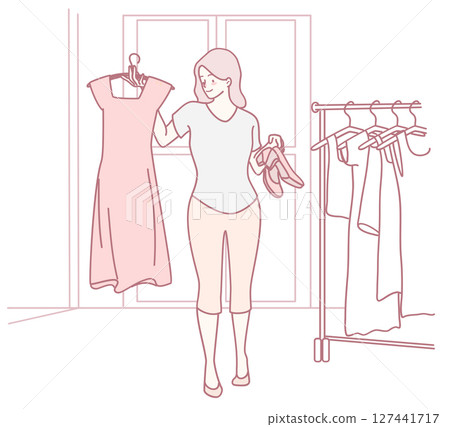 A woman making a fashion choice by selecting a dress and shoes in a stylish boutique store 127441717