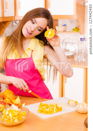 Woman housewife in kitchen cutting orange fruits 127442493