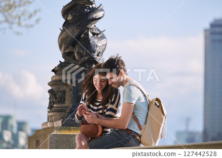 Couple, phone and travel holiday while at statue doing search on internet for map information on tourist trip. Man and woman with cellphone for social media content on foreign city journey in London Couple, phone and travel holiday while at statue doing search on internet for map information on tourist trip. Man and woman with cellphone for social media content on foreign city journey in London 127442528