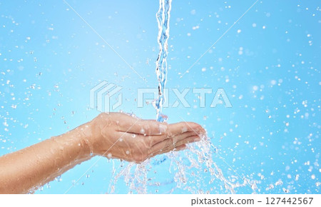 Hand, water and cleaning with a splash in studio on a blue background for hygiene or hydration. Mockup, health and wellness with a female washing under a water splash in the bathroom for skincare 127442567