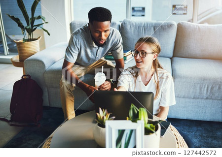 Students, friends and laptop study at sofa for education, learning and elearning lecture discussion. Interracial, help and studying together online for university exam preparation in living room. 127442572