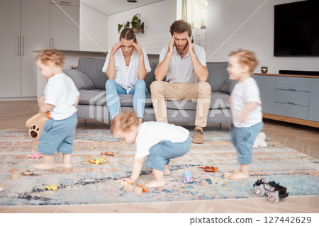 Parents, stress and busy with an adhd child running around a home living room with energy or motion blur. Family children and headache with a hyperactive kid in a lounge with a stressed mom and dad 127442629