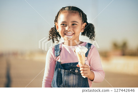 Girl, child and eating ice cream in city, street or urban road outdoors. Happy, smile and black kid enjoying fresh delicious gelato or dessert on a hot summer day, smiling and having fun time alone. 127442646