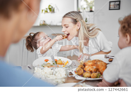 Happy family, mother and child eating chicken and vegetables in a healthy meal for dinner in Germany, Berlin. Food, nutrition and young girl feeding her hungry mom lunch at a home dining room table 127442661