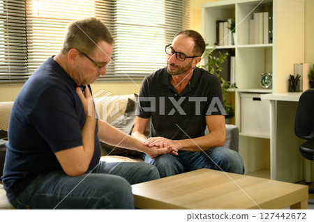 Adult son holds his father hand, symbolizing compassion, care and empathy Adult son holds his father hand, symbolizing compassion, care and empathy 127442672