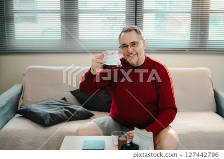 Elderly man enjoying a relaxing morning with a fresh pot of tea at home Elderly man enjoying a relaxing morning with a fresh pot of tea at home 127442796
