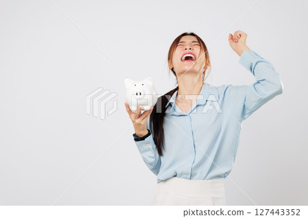 Piggy save money plan with happy woman with a fist up holding piggy bank excited to win in finance, showing success from smart saving and investment. isolated studio white background 127443352