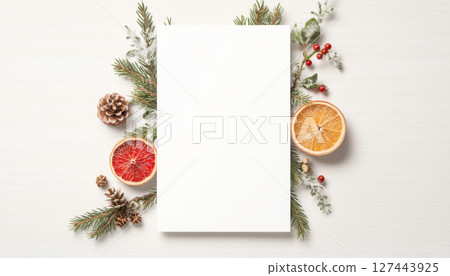 Blank white menu mockup surrounded by festive decorations, including pine cones, dried orange slices, and greenery, creating cheerful atmosphere 127443925
