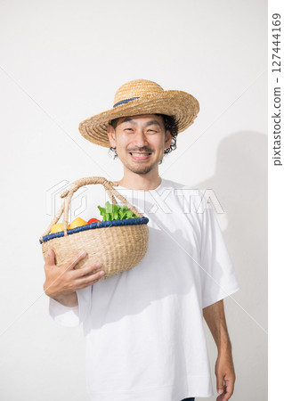 Image of a man holding harvested vegetables, smiling and looking at the camera, image of a farmer or farming Image of a man holding harvested vegetables, smiling and looking at the camera, image of a farmer or farming 127444169
