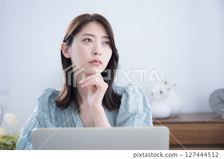 A cute woman thinking and wondering at her computer in her room. A slightly serious negative image. What should I do about changing jobs? A cute woman thinking and wondering at her computer in her room. A slightly serious negative image. What should I do about changing jobs? 127444512