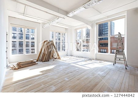 Empty room undergoing renovation with construction materials and ladders 127444842