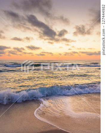 sea wave touch the sand beach at dawn. summer vacations in sozopol. nature after tranquil dream under glowing orange sky with dark clouds. scenic view of a seascape with calm water and relax mood 127444982