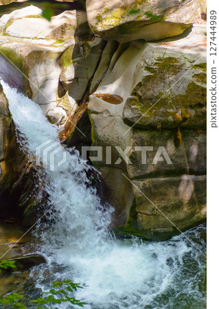 waterfall from rock among forest in summer. beautiful nature scenery with davir cascade on turychka river. discovery of the wild water stream. outdoor adventure in the beech wood of europe waterfall from rock among forest in summer. beautiful nature scenery with davir cascade on turychka river. discovery of the wild water stream. outdoor adventure in the beech wood of europe 127444989