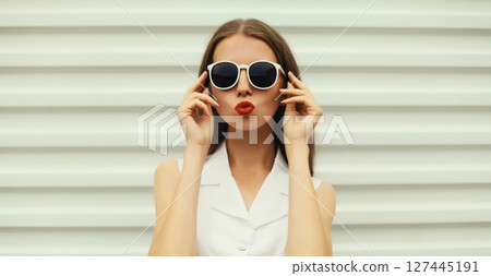 Fashion portrait of beautiful young woman blowing a kiss in white glasses, stylish girl posing 127445191