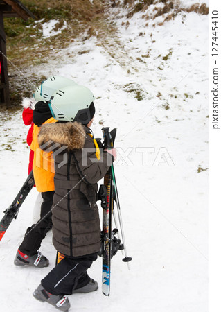 A group of excited children eagerly getting ready for a fun filled day of skiing on the pristine, fresh snow at a bustling winter sports resort on a crisp, chilly morning A group of excited children eagerly getting ready for a fun filled day of skiing on the pristine, fresh snow at a bustling winter sports resort on a crisp, chilly morning 127445410