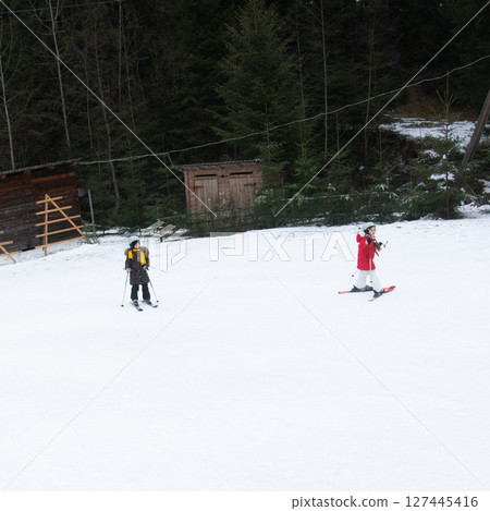 Skiing adventure unfolds in the snowy woods with two enthusiasts navigating a pristine white landscape on a crisp winter day Skiing adventure unfolds in the snowy woods with two enthusiasts navigating a pristine white landscape on a crisp winter day 127445416