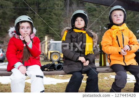 Kids waiting excitedly on a snowy day in cozy winter outfits at a ski resort, foreshadowing thrilling adventures ahead 127445420