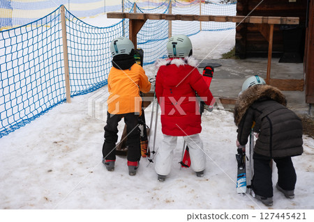 Children prepare for a fun day of skiing in the winter wonderland with fluffy snow and exciting slopes at a mountain resort in the afternoon light 127445421