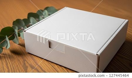 White Cardboard Box with Eucalyptus Leaves on Wooden Surface Minimalist Packaging Mockup 127445464