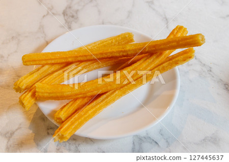 Traditional spanish dessert churros - fried choux pastry on a table. Top view 127445637