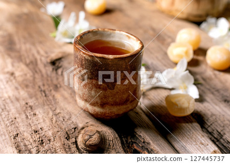Ceramic cup herbal tea wooden table white flowers petals rustic natural setting healthy drink relaxation moment Ceramic cup herbal tea wooden table white flowers petals rustic natural setting healthy drink relaxation moment 127445737