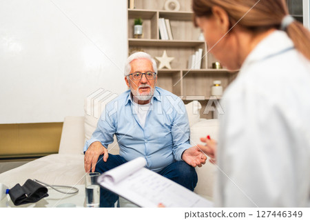 Female doctor examining older senior man in doctor office or at home. Old man patient and doctor have consultation in hospital room. Medicine healthcare medical checkup. Visit to doctor 127446349