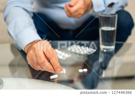 Hands with pills. Senior man hands with medical pill and glass of water. Mature old senior grandfather taking medication cure pills vitamin. Age prescription medicine healthcare therapy concept 127446366