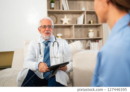 Senior man doctor examining young woman in doctor office clinic or at home. Girl patient and doctor have consultation in hospital room. Medicine healthcare medical checkup. Visit to doctor Senior man doctor examining young woman in doctor office clinic or at home. Girl patient and doctor have consultation in hospital room. Medicine healthcare medical checkup. Visit to doctor 127446395