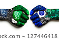 Two hands shaking hands with a circuit board in the middle 127446418