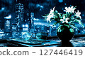 A vase of flowers sitting on top of a desk next to a laptop computer 127446419