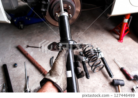 Car Shock Absorber or Strut, A mechanic hand holds a new black shock absorber or strut  127446499