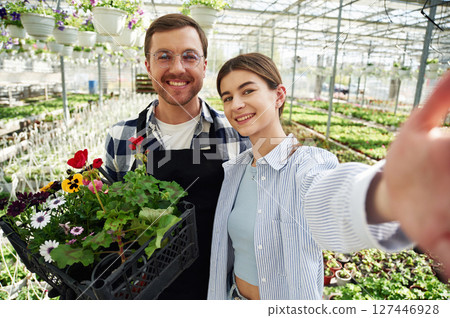 Making selfie, smiling. Florist man and woman are working together in bright greenhouse Making selfie, smiling. Florist man and woman are working together in bright greenhouse 127446928