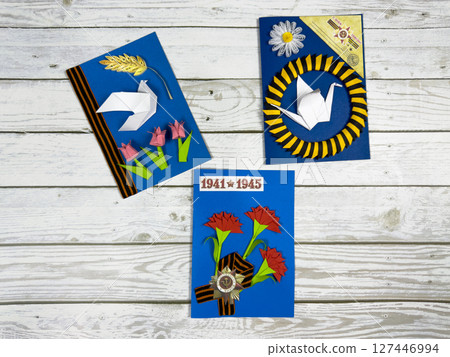 Three handmade cards for Victory Day with paper crafts. Featuring red carnations, origami dove and crane, St. George ribbon, and date 1941-1945 in memory of WWII 127446994
