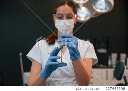 Doctor in blue glowes is standing and holding equipment. In the stomatological cabinet Doctor in blue glowes is standing and holding equipment. In the stomatological cabinet 127447606