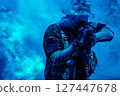 Soldier in camouflage outfit with rifle and tactical gear aiming amidst blue smoke in a dynamic, intense scene. 127447678