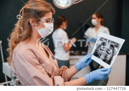 Doctors are indoors. Woman holding and looking at x-ray. In the stomatological cabinet 127447726