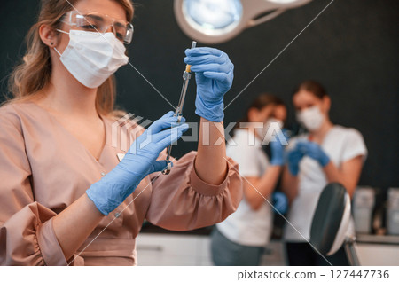 Four women. Doctor holding syringe. In the stomatological cabinet Four women. Doctor holding syringe. In the stomatological cabinet 127447736