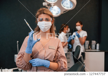 Four women. Doctor holding syringe. In the stomatological cabinet Four women. Doctor holding syringe. In the stomatological cabinet 127447737