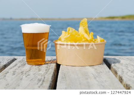 plastic cup of beers and potato chips on a dock plastic cup of beers and potato chips on a dock 127447924