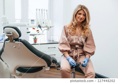 Beautiful woman doctor is sitting. In the stomatological cabinet Beautiful woman doctor is sitting. In the stomatological cabinet 127448202